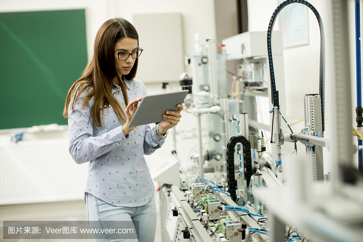 年輕女子在電子車間拿著平板電腦